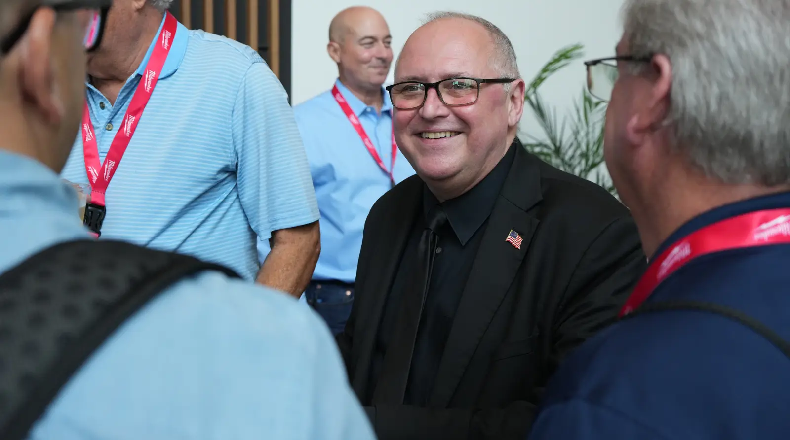 A contractor smiling and talking with colleagues at a construction industry conference
